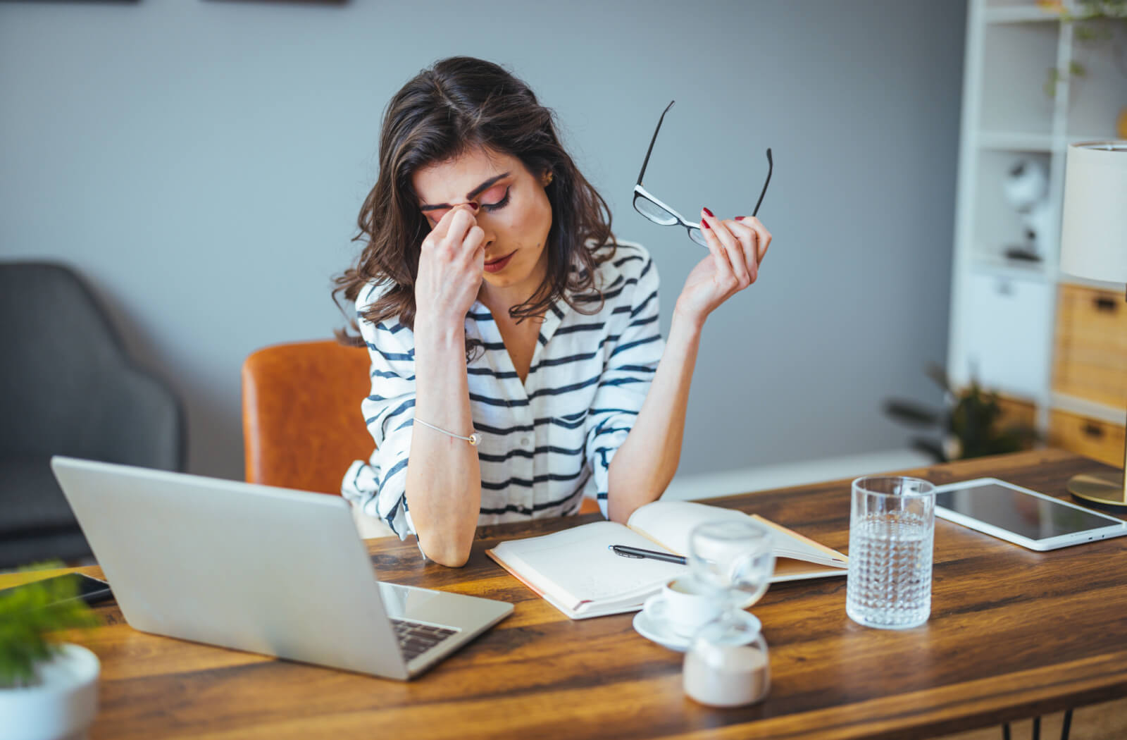 Fatigued businesswoman taking off glasses tired of computer work and suffering from dry eye. 