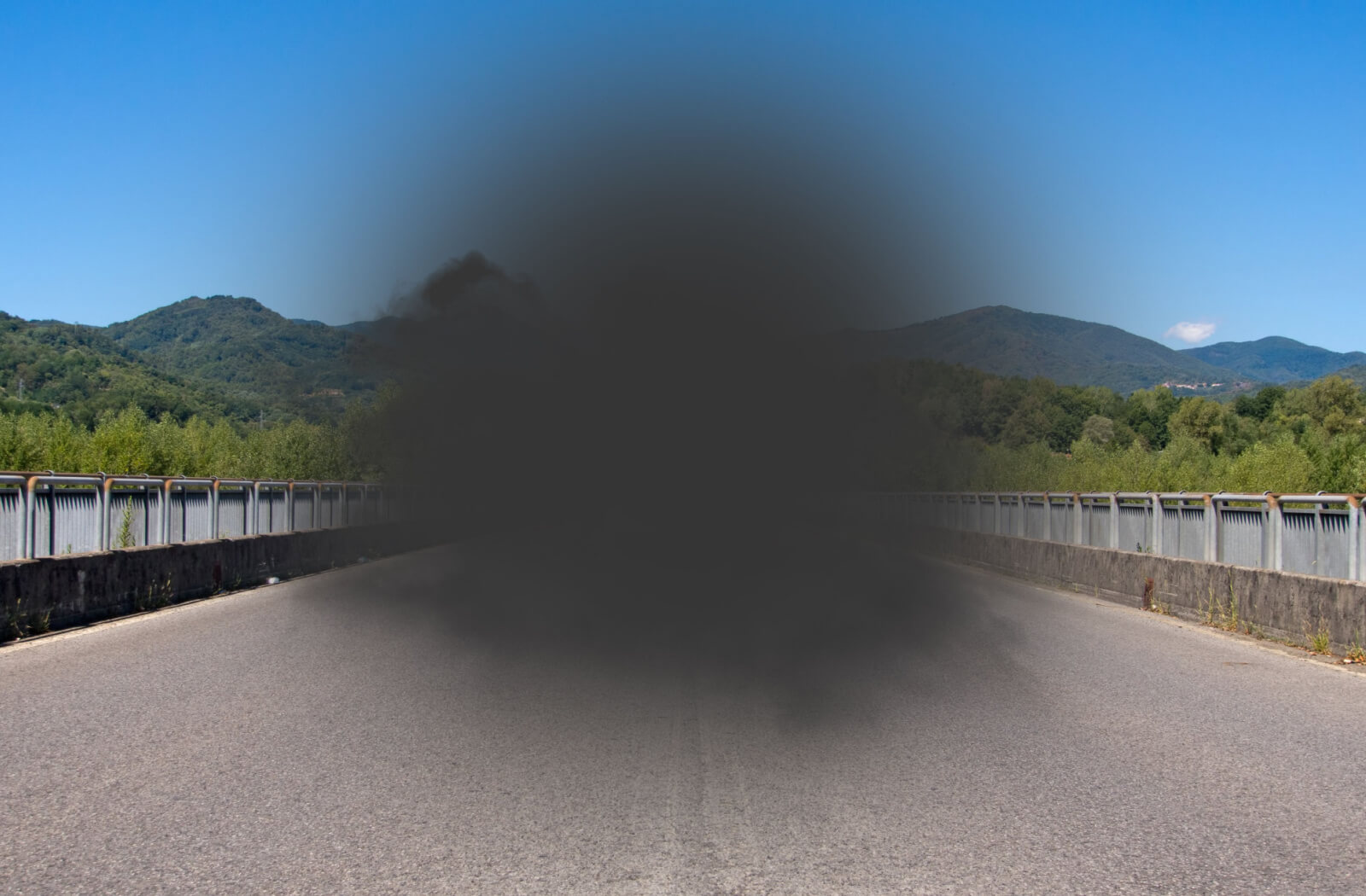 A view of a concrete bridge on a sunny day with a dark grey spot blocking central vision, representing the POV of a person with macular degeneration.