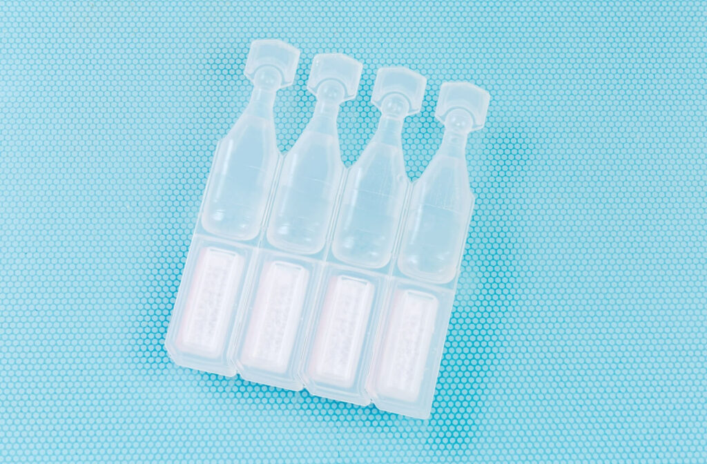 A set of disposable, unmarked eye drops lying on a blue mat.